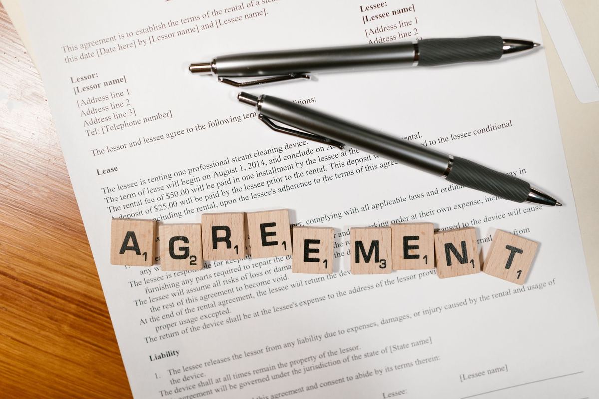 Wooden letter tiles spelling “agreement” on a printed rental agreement