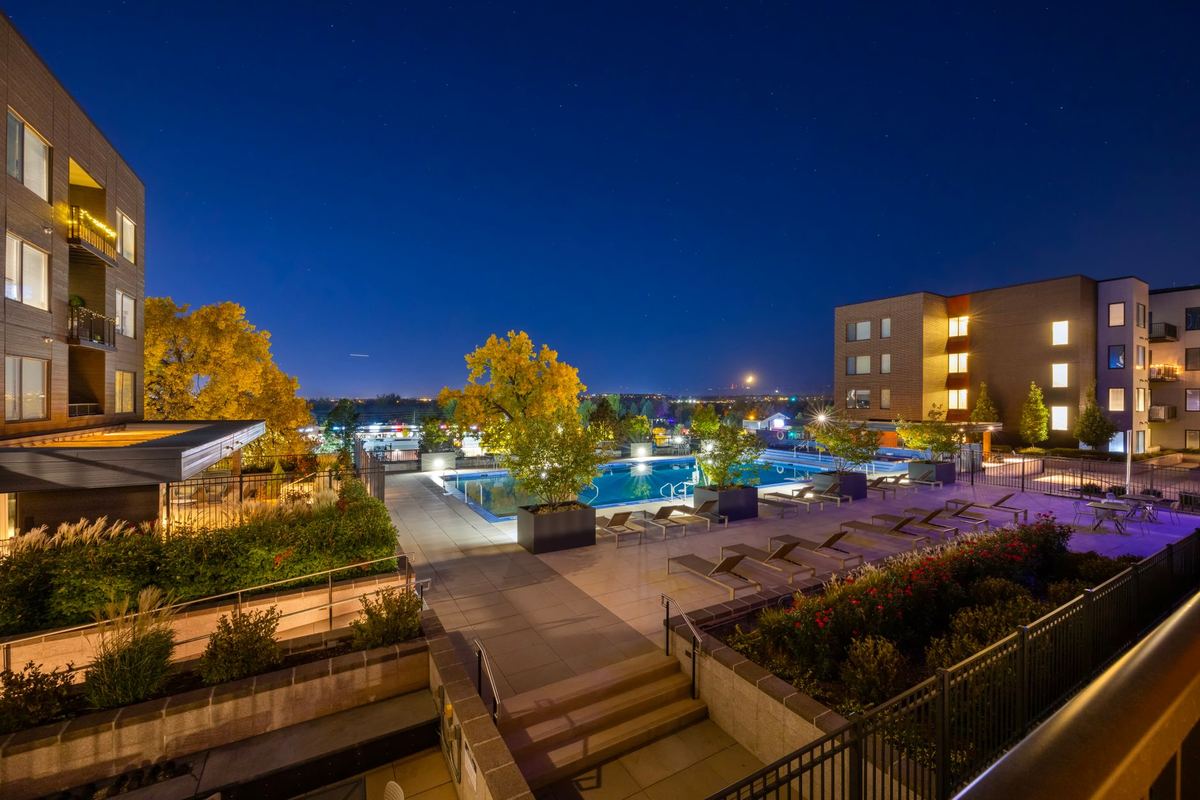 Apartment community pool deck lit at dusk between buildings
