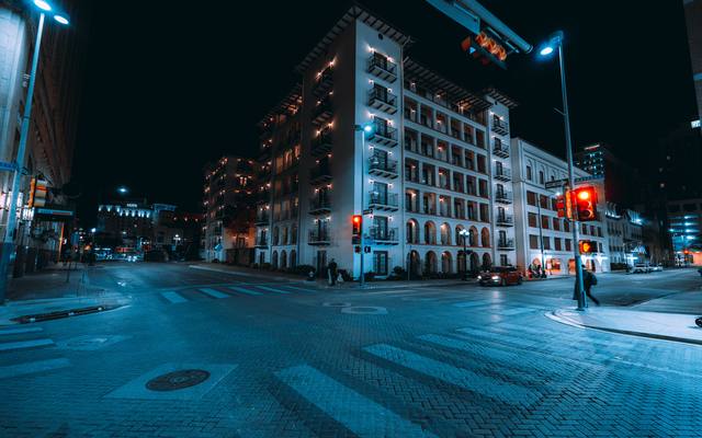 Historic downtown San Antonio buildings at a brick-paved crossing at night
