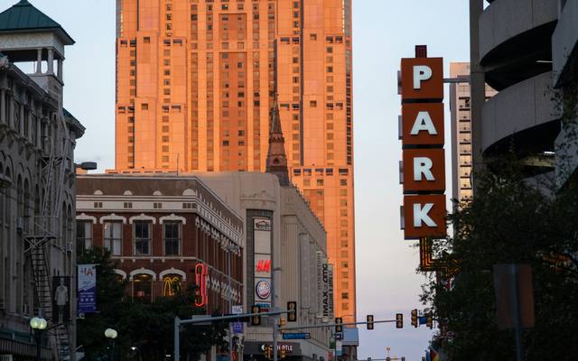 Downtown San Antonio street with a vertical parking sign and a brick office tower