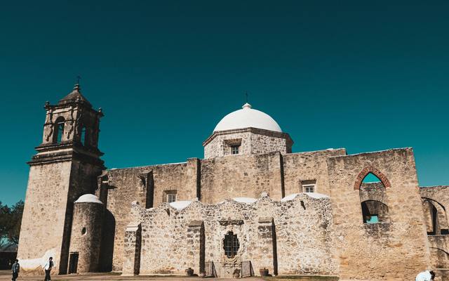 Stone walls and bell tower of Mission San José at dusk in San Antonio