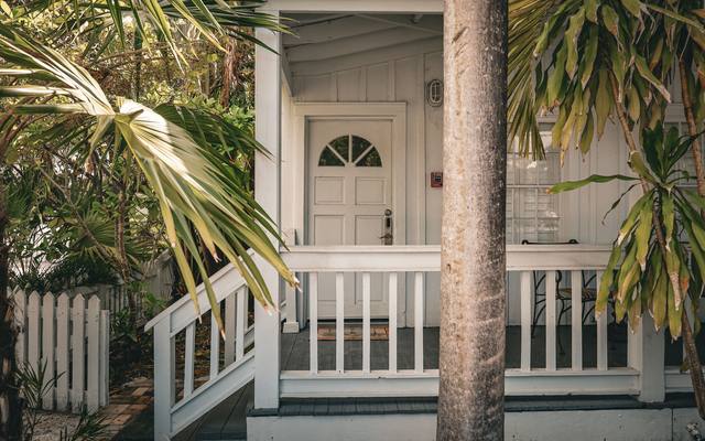 Covered wooden porch of a small rental house behind a white picket fence