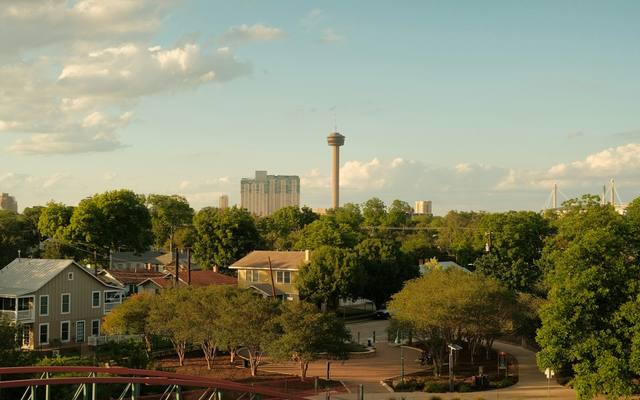 Footbridge and tree-shaded houses south of downtown San Antonio with the Tower of the Americas beyond