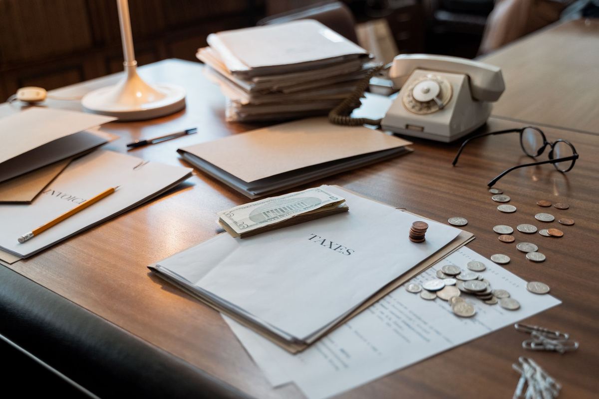 Wooden desk with a tax envelope, loose coins, folders and a rotary telephone