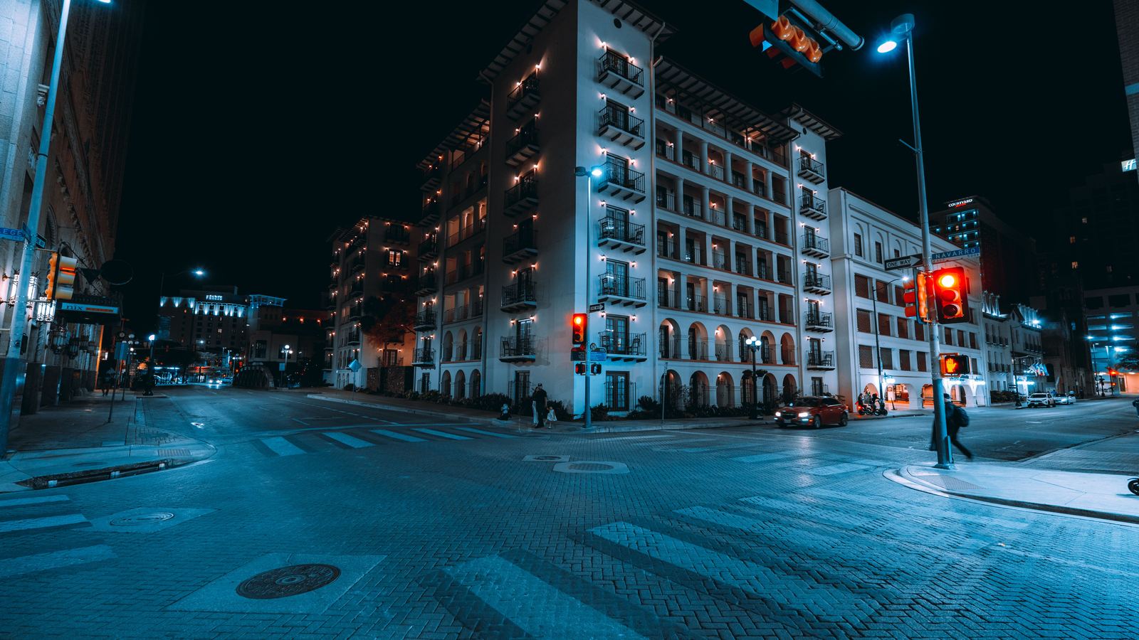 Historic downtown San Antonio buildings at a brick-paved crossing at night
