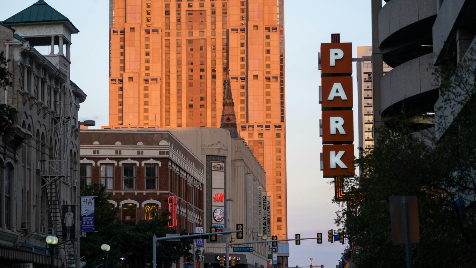 Downtown San Antonio street with a vertical parking sign and a brick office tower