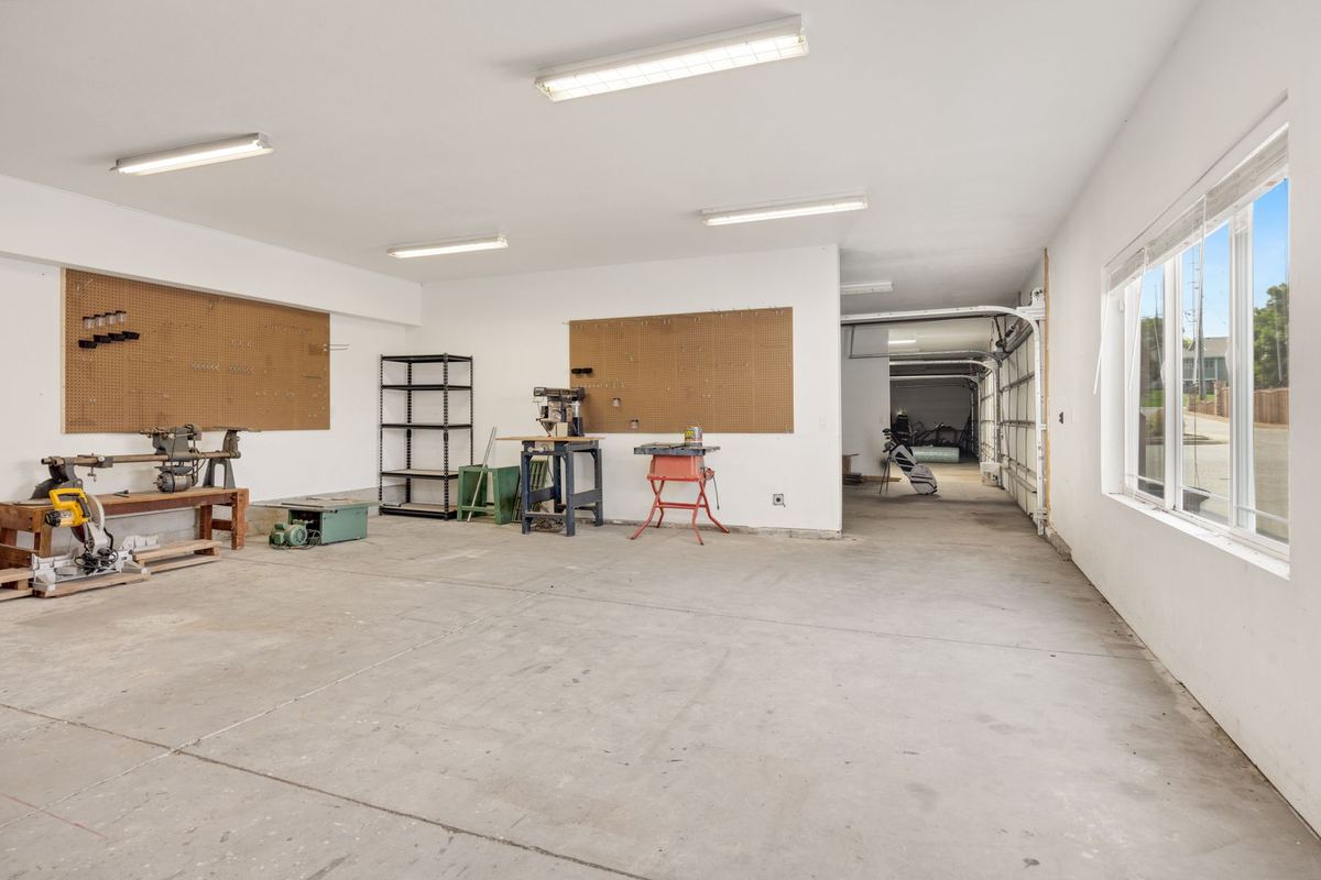 Empty workshop space with pegboards, work benches and a roll-up door