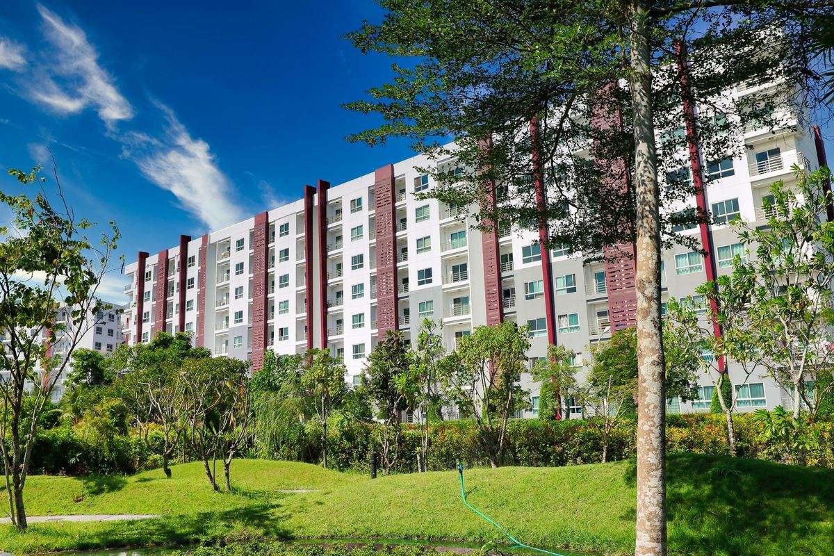 Garden apartment building set behind mature trees and an open lawn