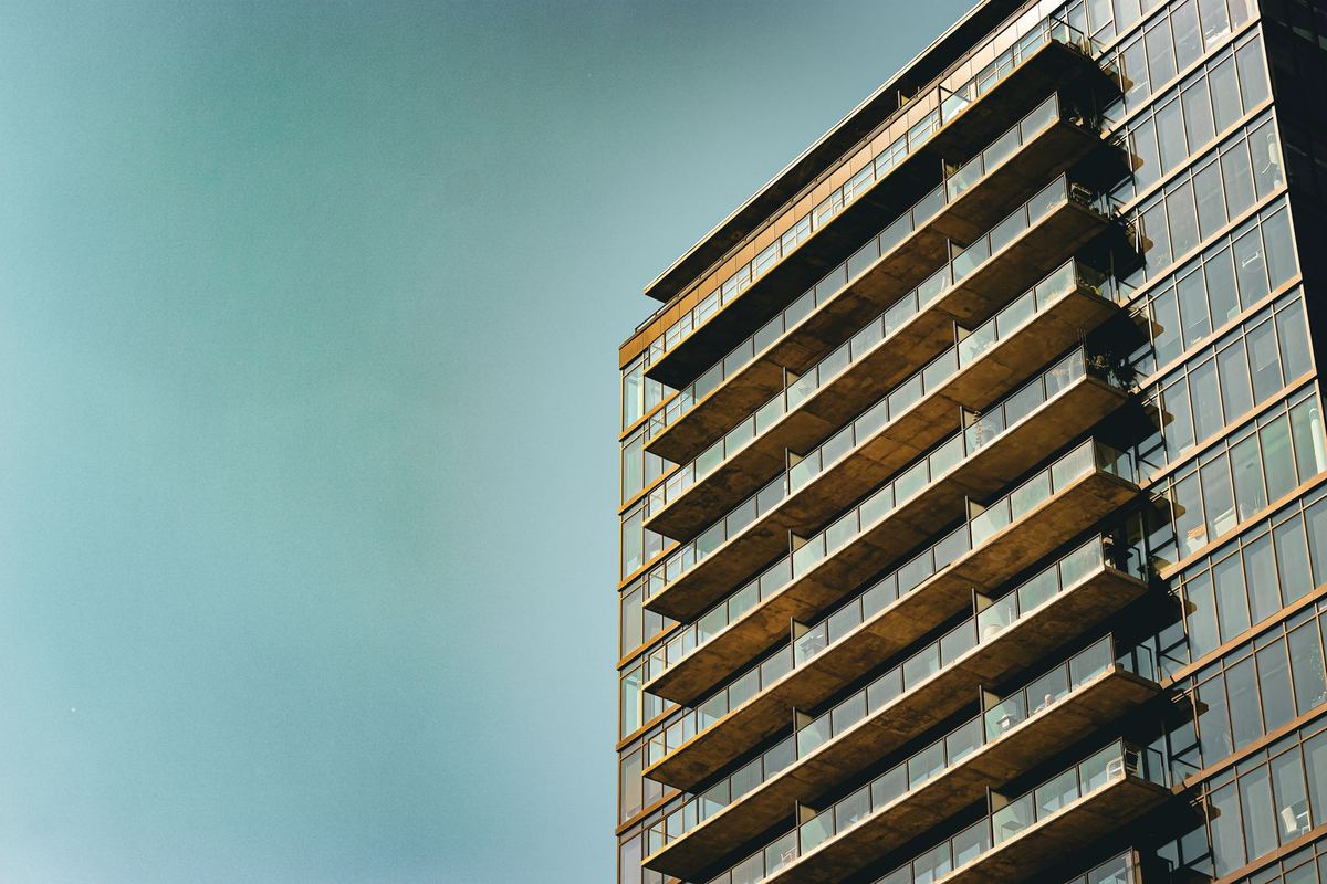 High-rise apartment tower with stacked glass balconies against a clear sky
