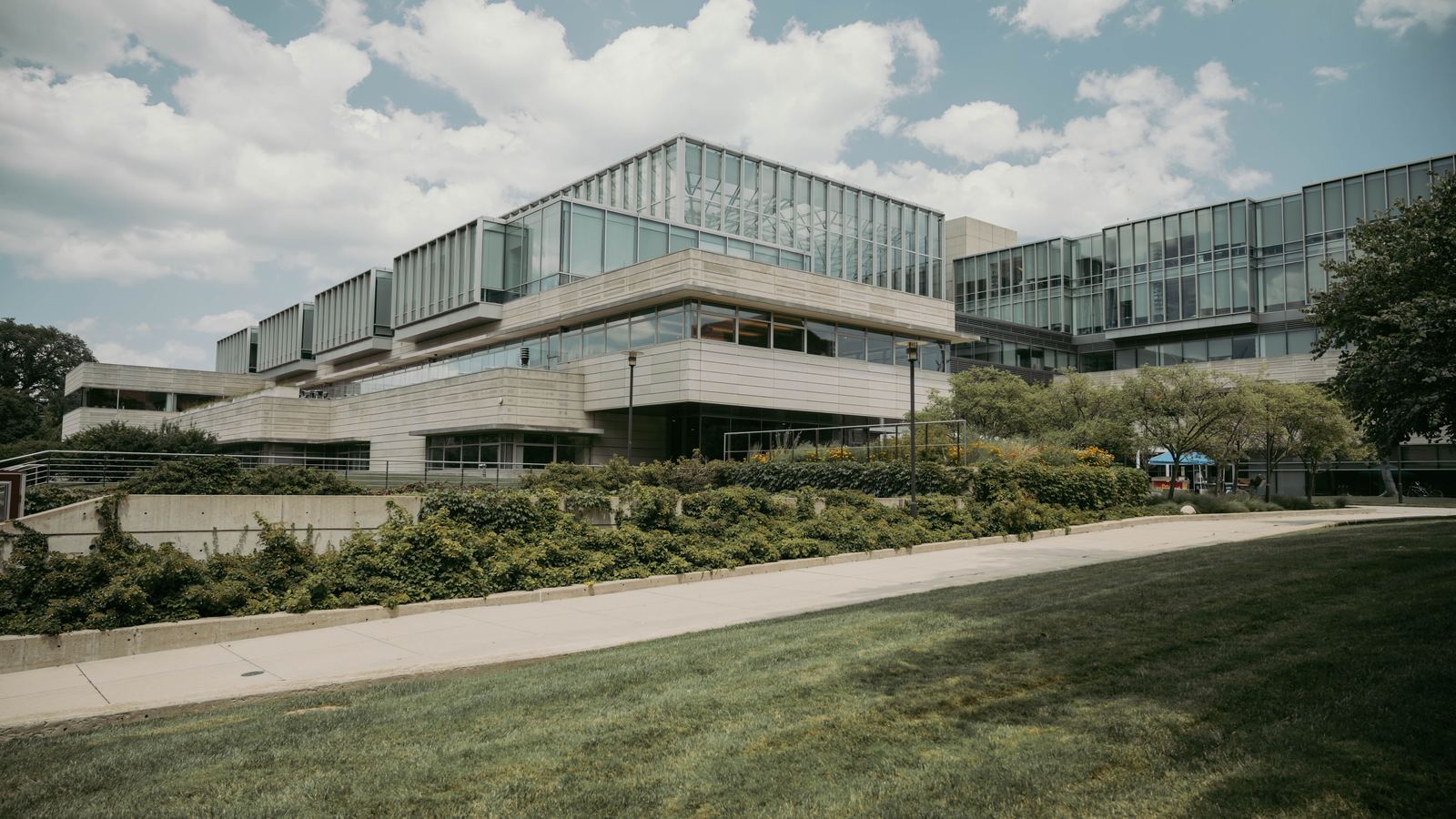 Glass and concrete institutional buildings above a landscaped lawn