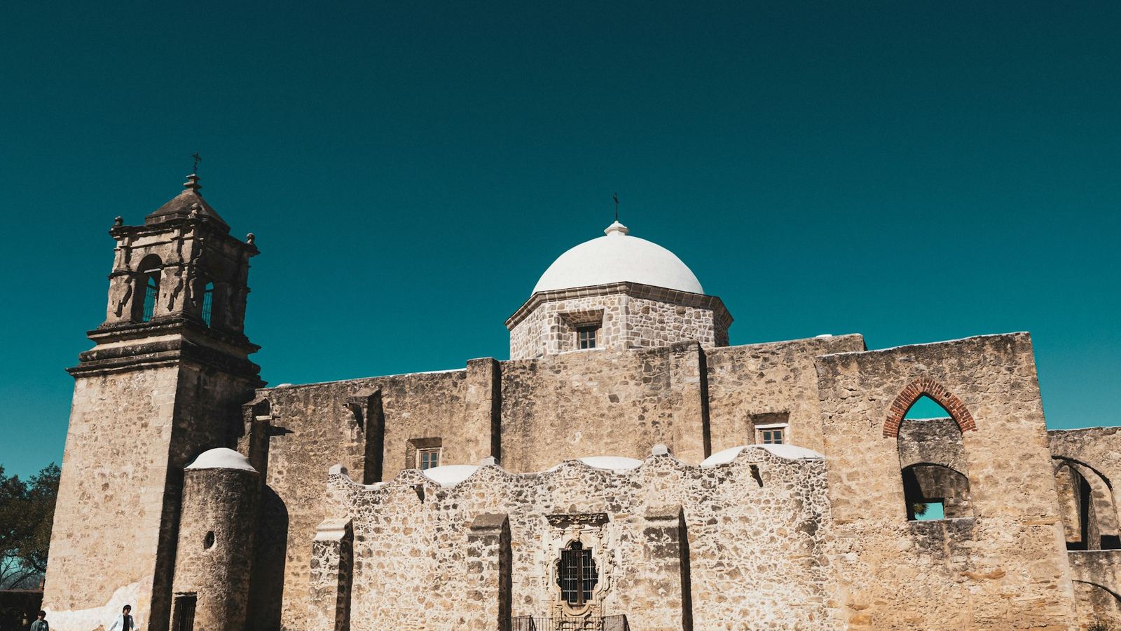 Stone walls and bell tower of Mission San José at dusk in San Antonio