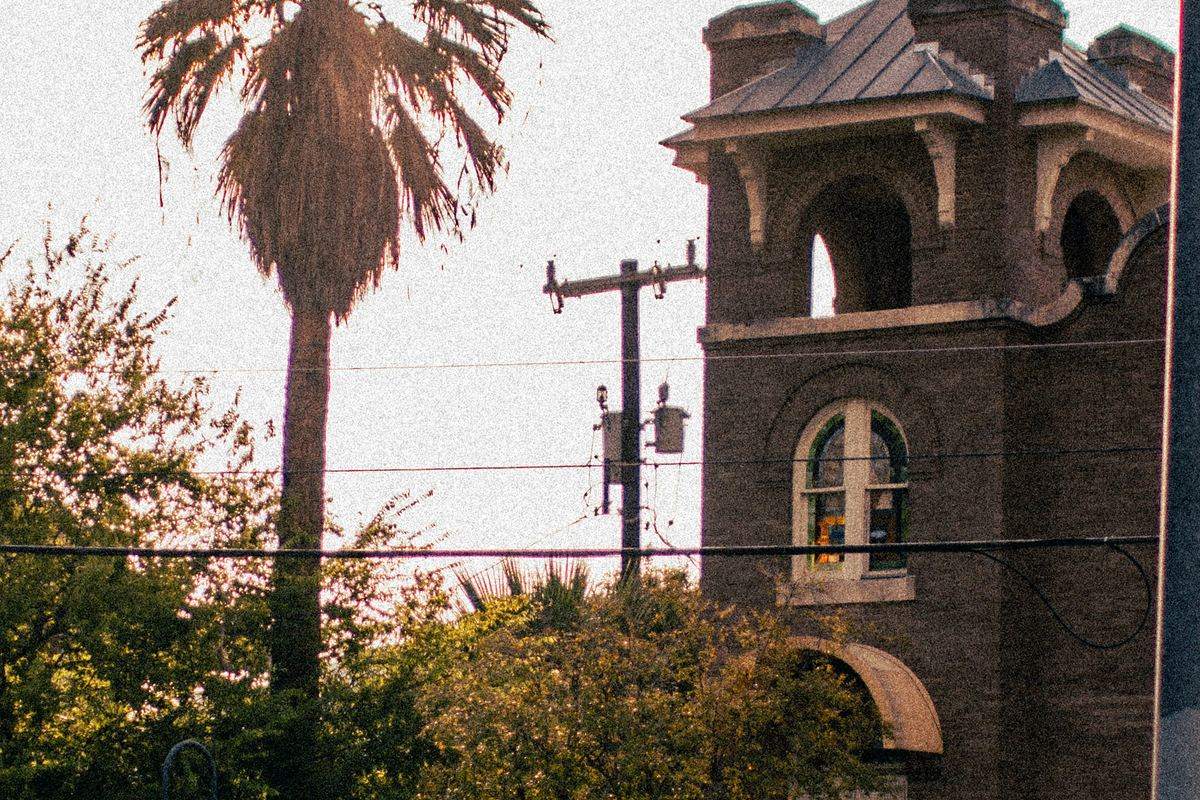 Palm tree beside a brick Victorian tower at sunset in San Antonio